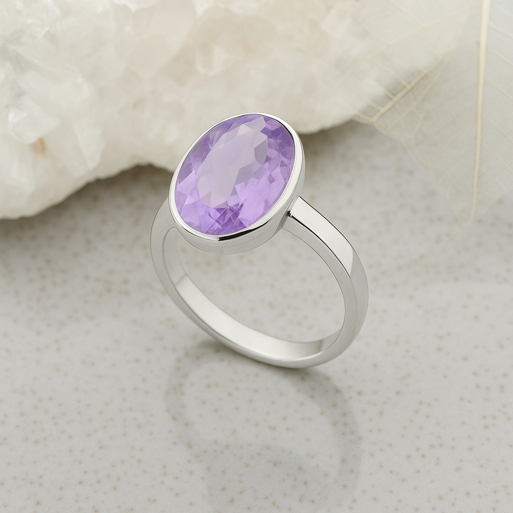 An oval faceted amethyst stone set in a sterling silver ring with a high polish finish.