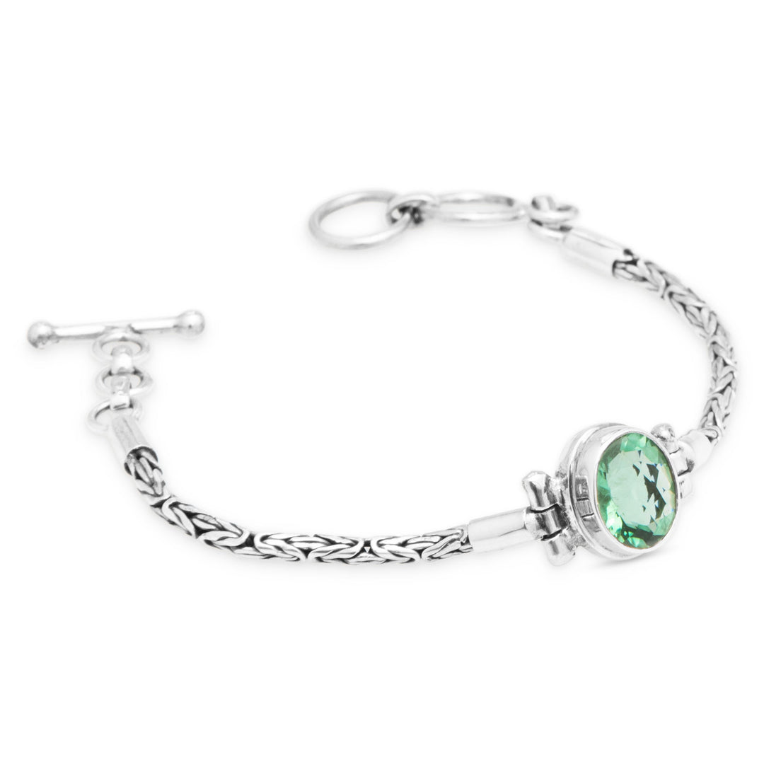 Silver bracelet with a green gemstone on a white background