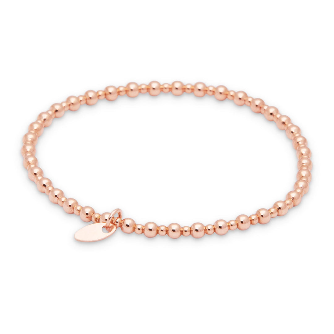 A rose gold-colored bracelet with beads, featuring a high polish finish and a small charm.