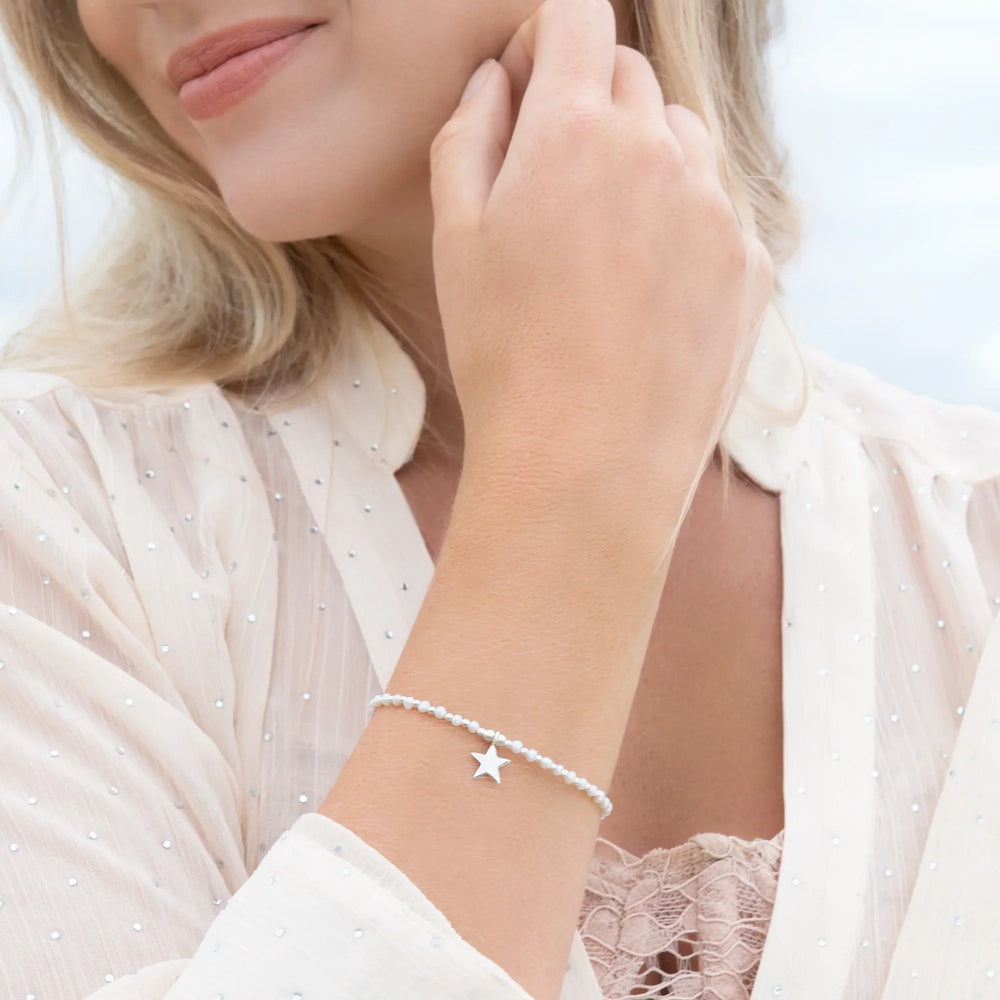 Woman wearing a delicate bracelet with a star charm on a blurred background
