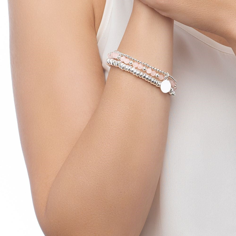 A silver bracelet with a polished finish, featuring a circular disc charm, displayed on female model