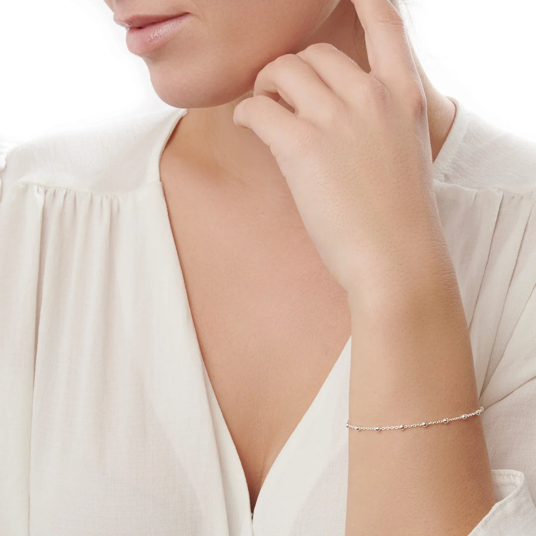 A sterling silver bracelet with a chain link design and small spherical embellishments, featuring a secure lobster claw clasp.