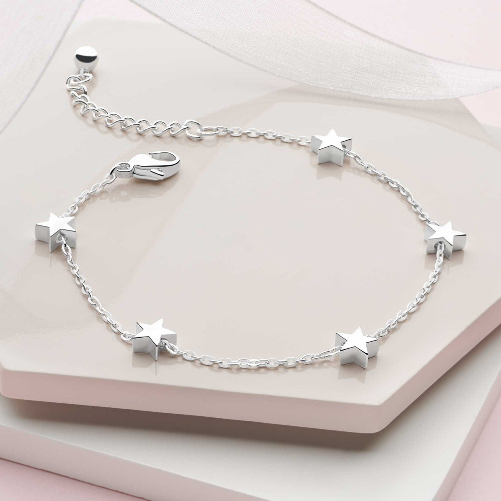 A silver bracelet adorned with a series of small silver stars, featuring a secure lobster-claw clasp on neutral background