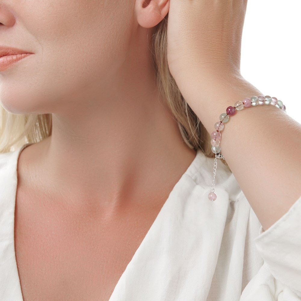 A fluorite bead bracelet with a mix of green and purple tones, showcased on a silver dish alongside a silver star charm.