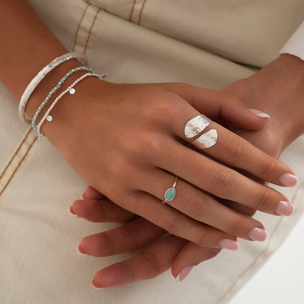Close-up of hands wearing multiple rings and bracelets on a neutral background