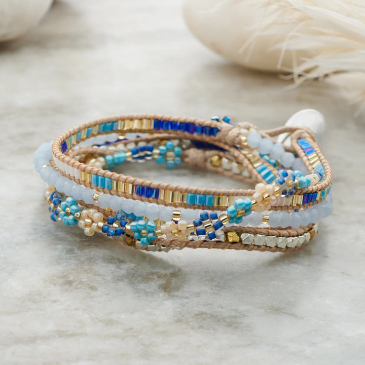 Stack of beaded bracelets with blue and gold accents on a light background
