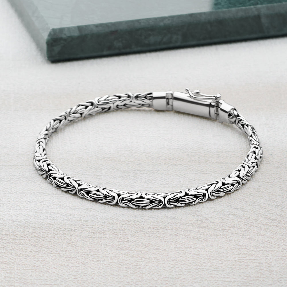 Silver bracelet with intricate design on a light gray surface