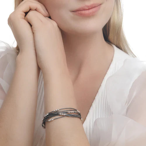 A bracelet with silver beads threaded through a grey cord, displayed on a female model