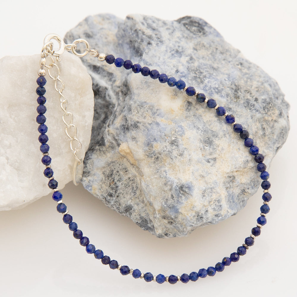 A bracelet with faceted lapis lazuli beads and silver beads, finished with a high polish.