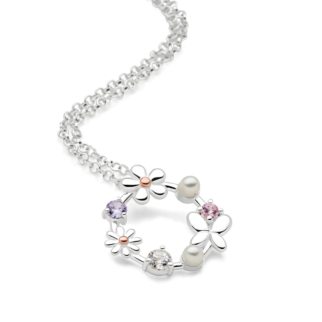 A silver necklace with a circular pendant featuring butterflies, daisies, pearls, and sparkling cubic zirconia embellishments.
