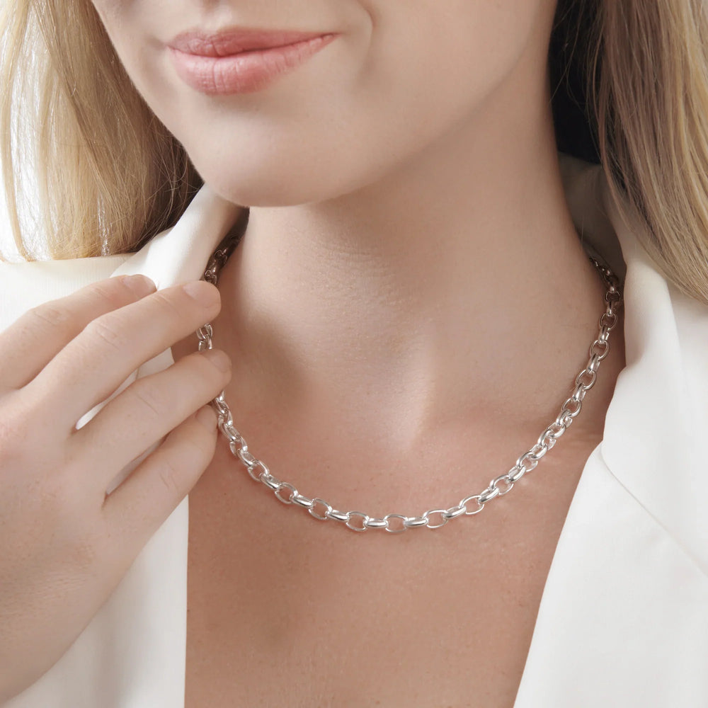 A model wearing a bold, polished silver chunky link chain necklace featuring uniform oval links and an adjustable extender clasp.