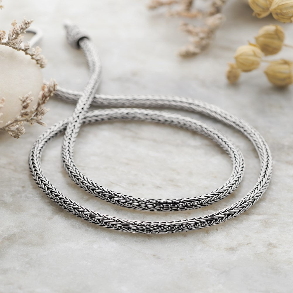A close-up image of a 925 sterling silver chain with a classic Balinese weave, featuring a high polish and oxidised finish.