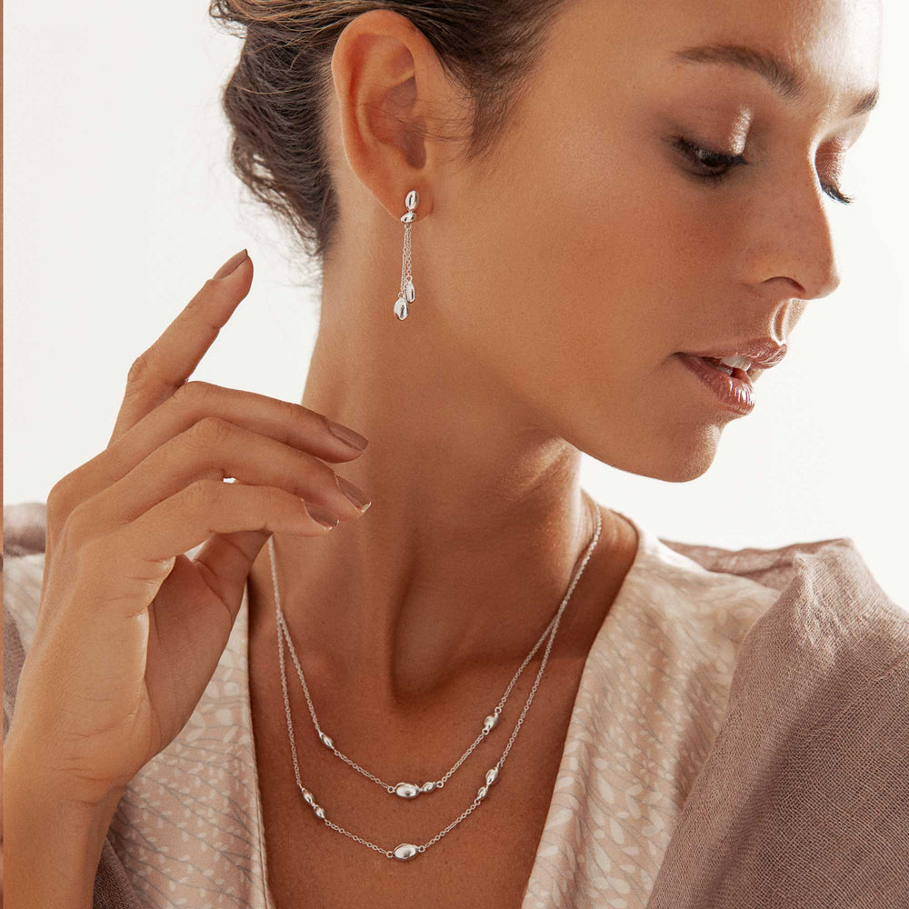 Woman wearing a double strand silver necklace with rounded pebble shaped beads
