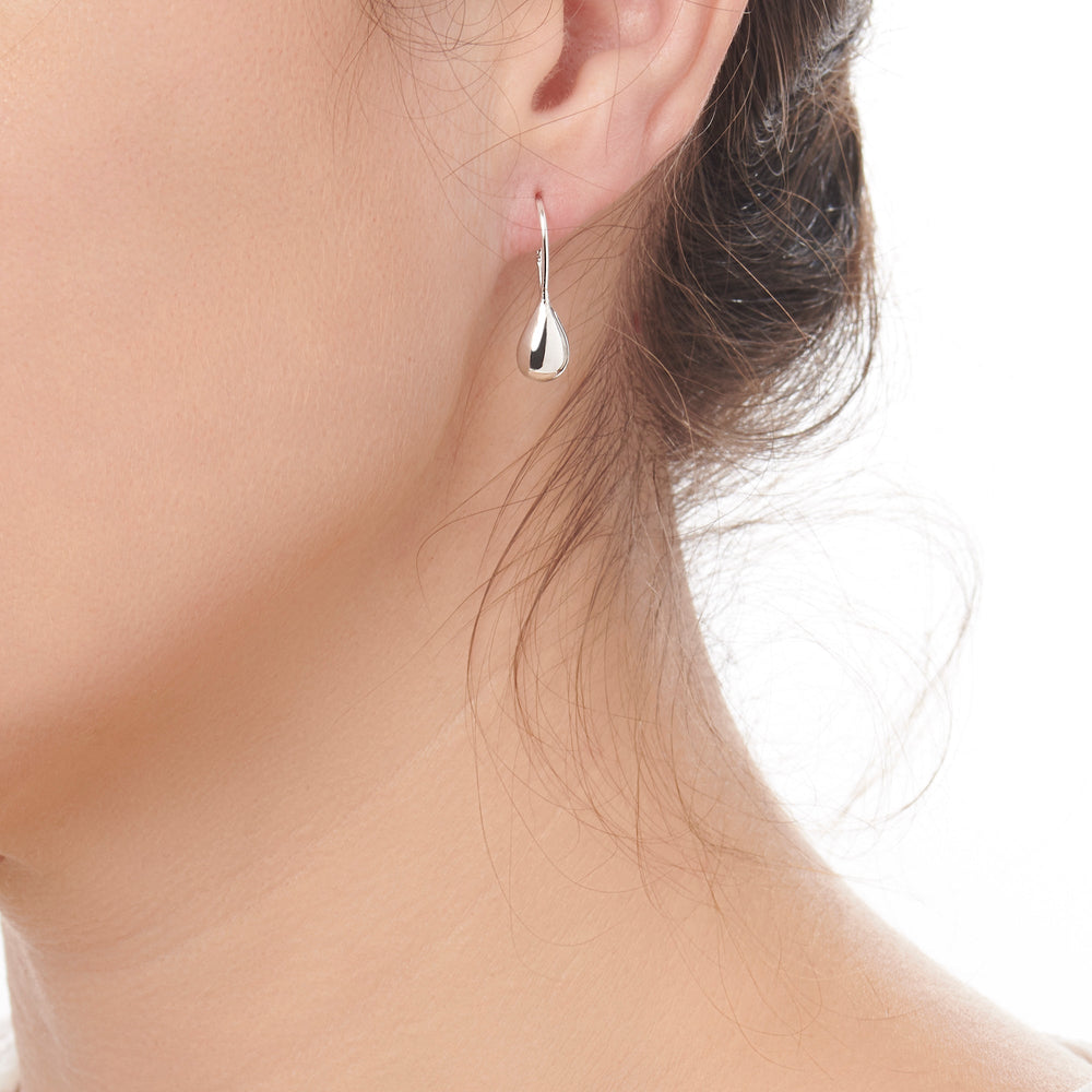 A pair of silver drop earrings with a high polish finish, showing a teardrop shape design on model.