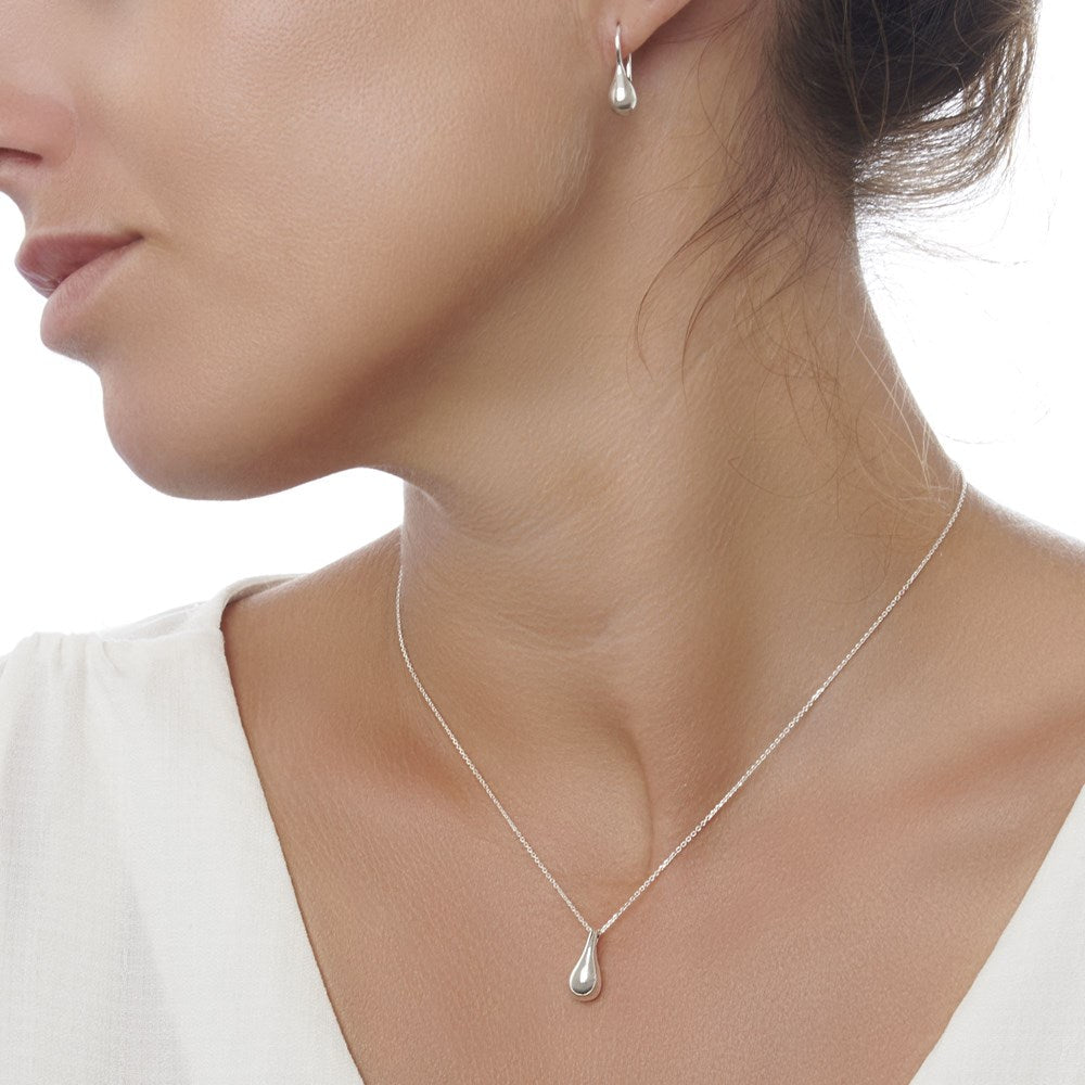 A pair of silver drop earrings with a high polish finish, showing a sleek, teardrop shape on model.