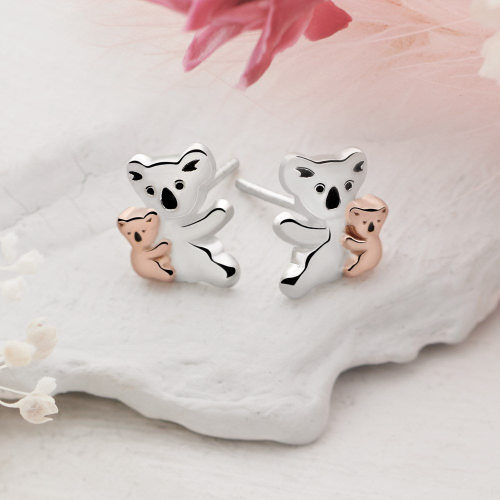A pair of stud earrings featuring a silver koala with a rose gold koala baby on each earring.