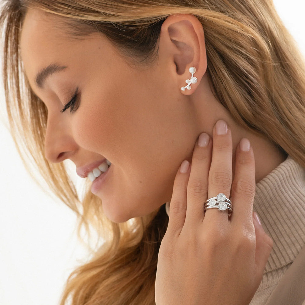 Close-up of a woman wearing a silver earring and ring on a white background