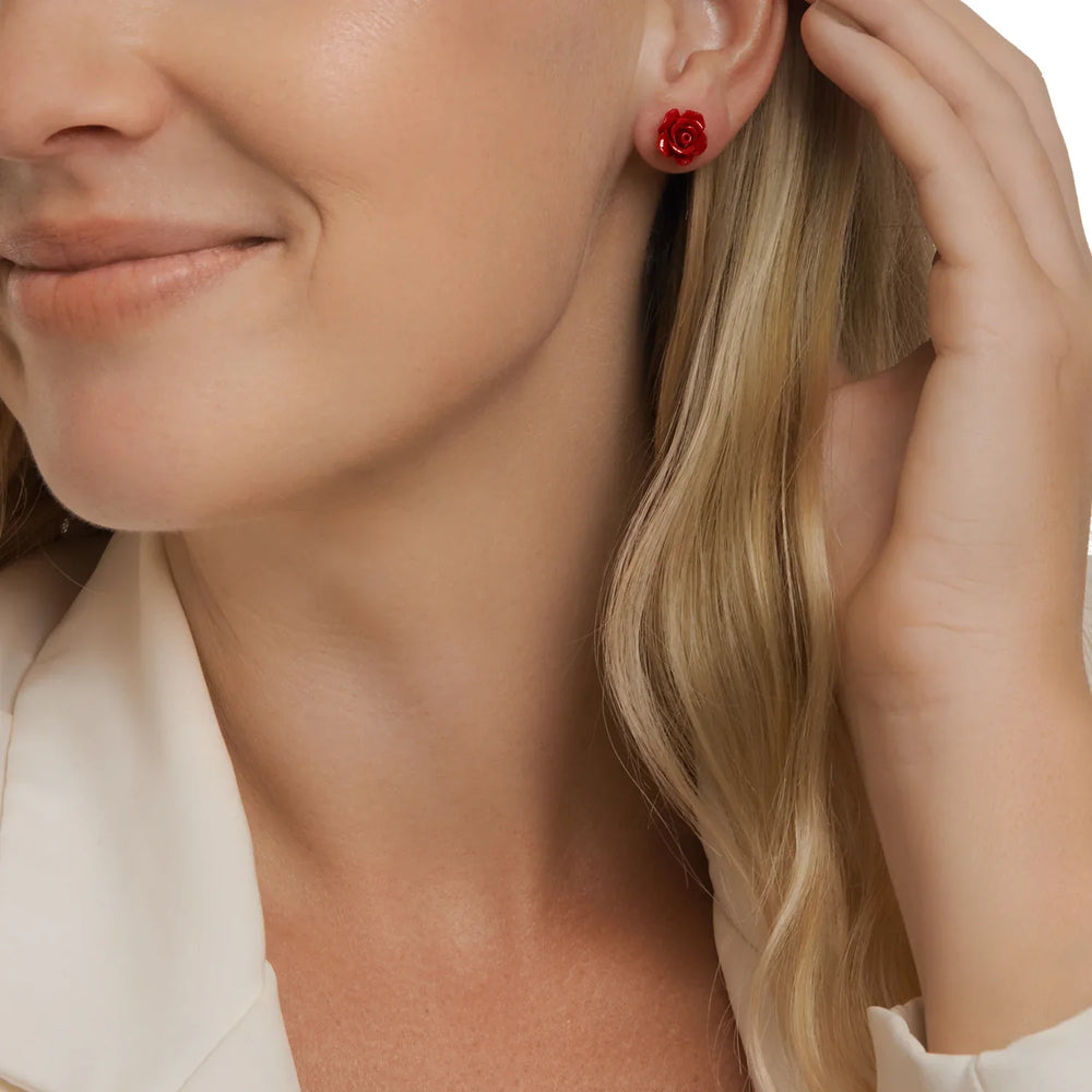 Close-up of a woman wearing a red rose earring with a blurred background
