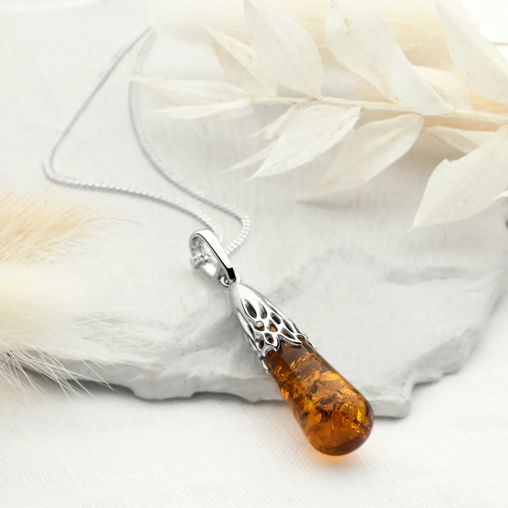 A rhodium-plated sterling silver pendant with a teardrop-shaped amber stone suspended from a silver chain.