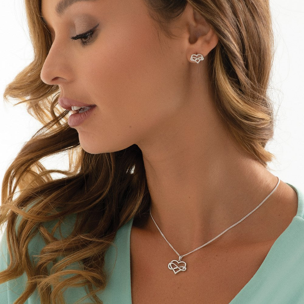 A woman wearing a silver heart pendant embracing the symbol of infinity, attached to a silver chain.