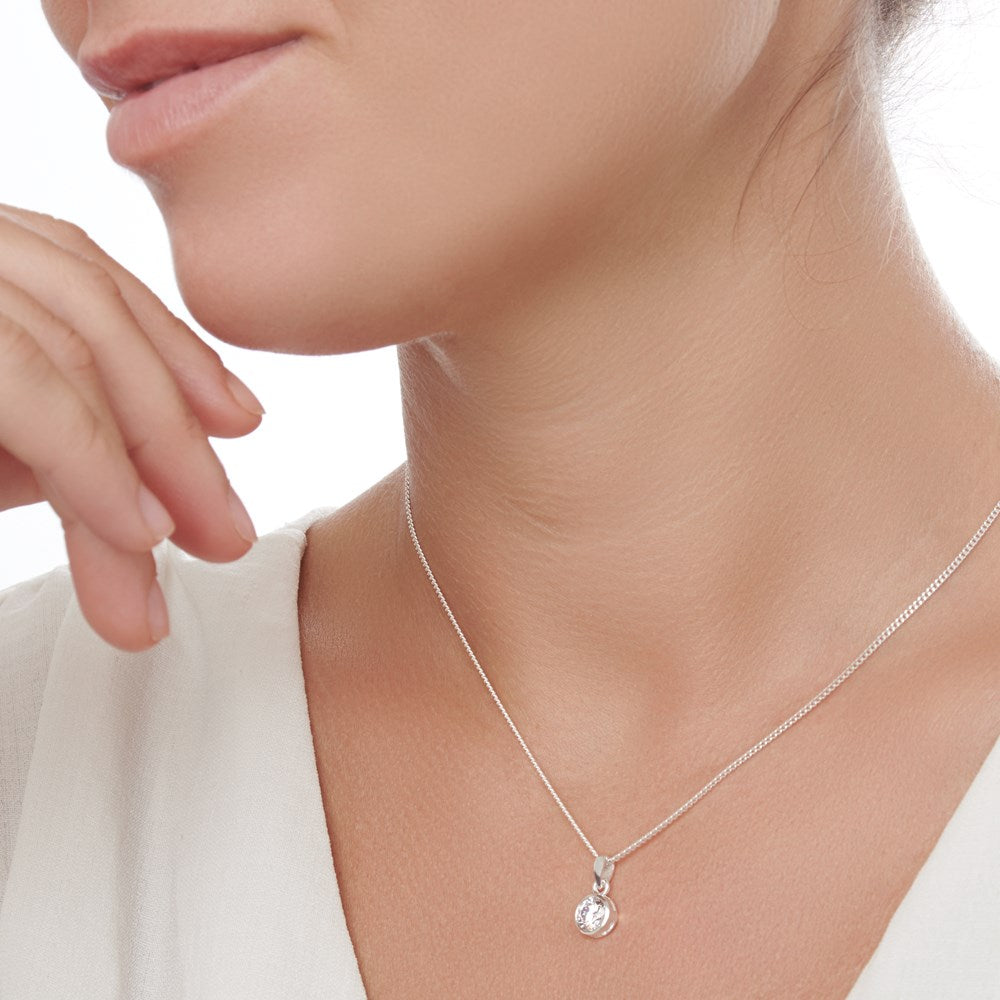 A sterling silver pendant with a sparkling cubic zirconia stone included on a 40cm curb chain on woman model. 