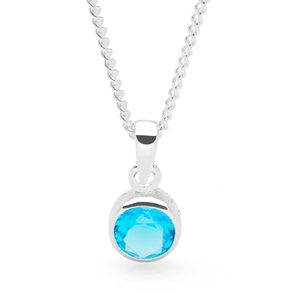 A sterling silver pendant with a turquoise blue cubic zirconia set in a round, bezel-style setting, attached to a curb chain.