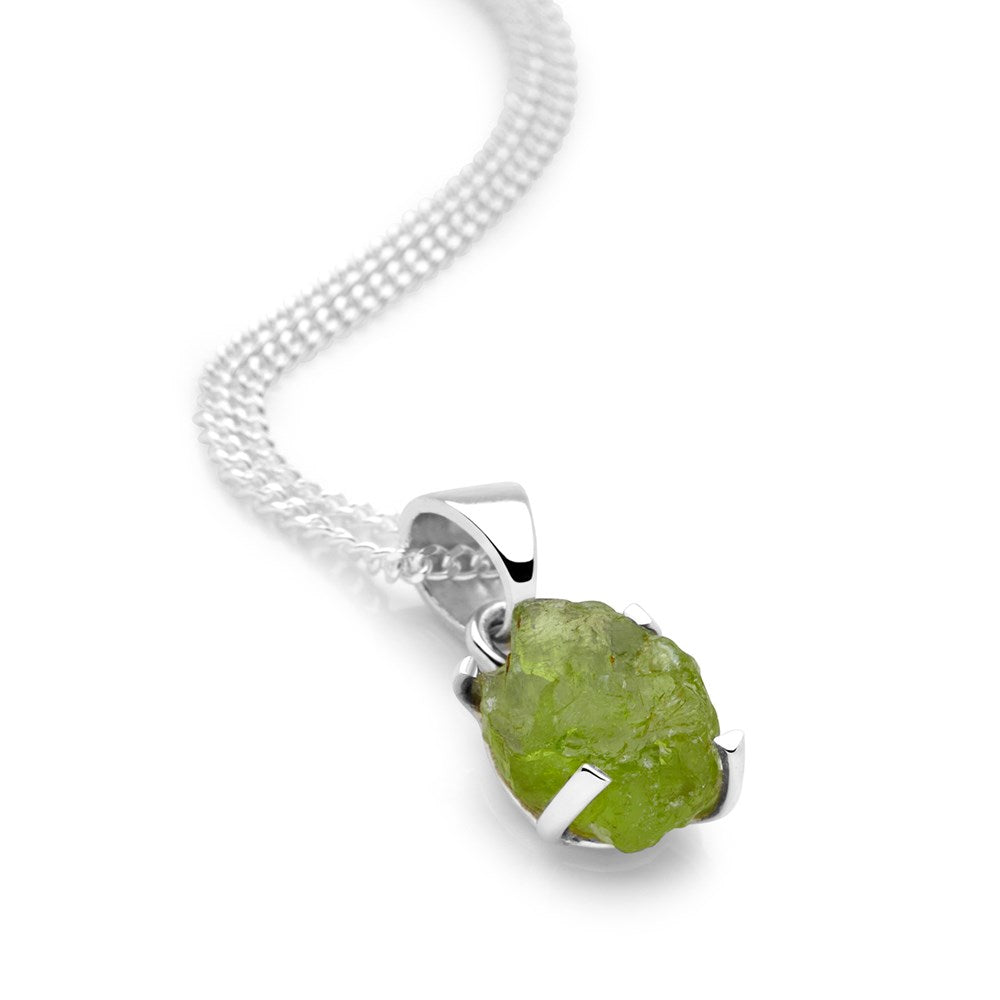 A bright green peridot pendant in a sterling silver setting, displayed on a silver chain against a white background.