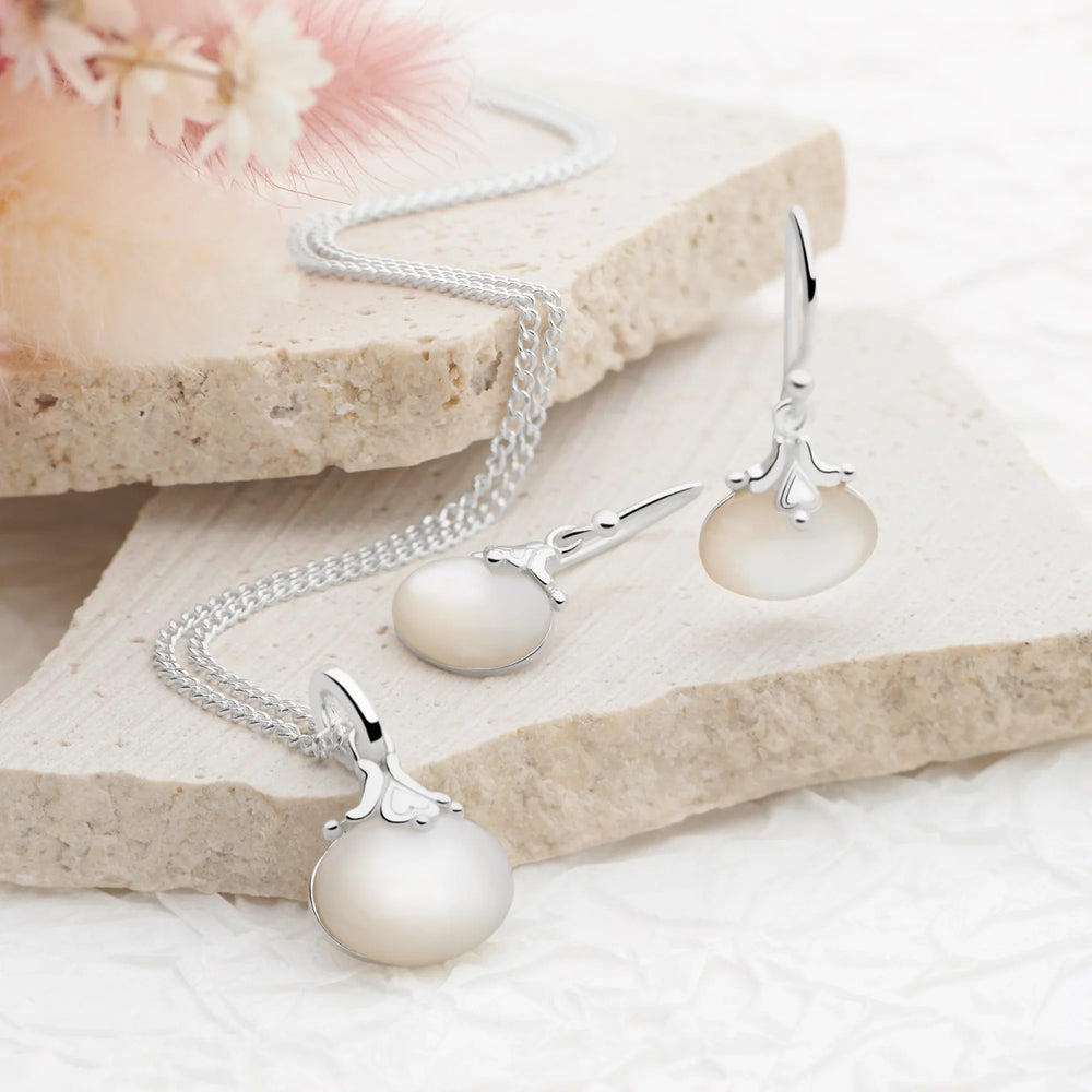 A silver curb chain necklace with a round mother of pearl pendant and a silver clasp.