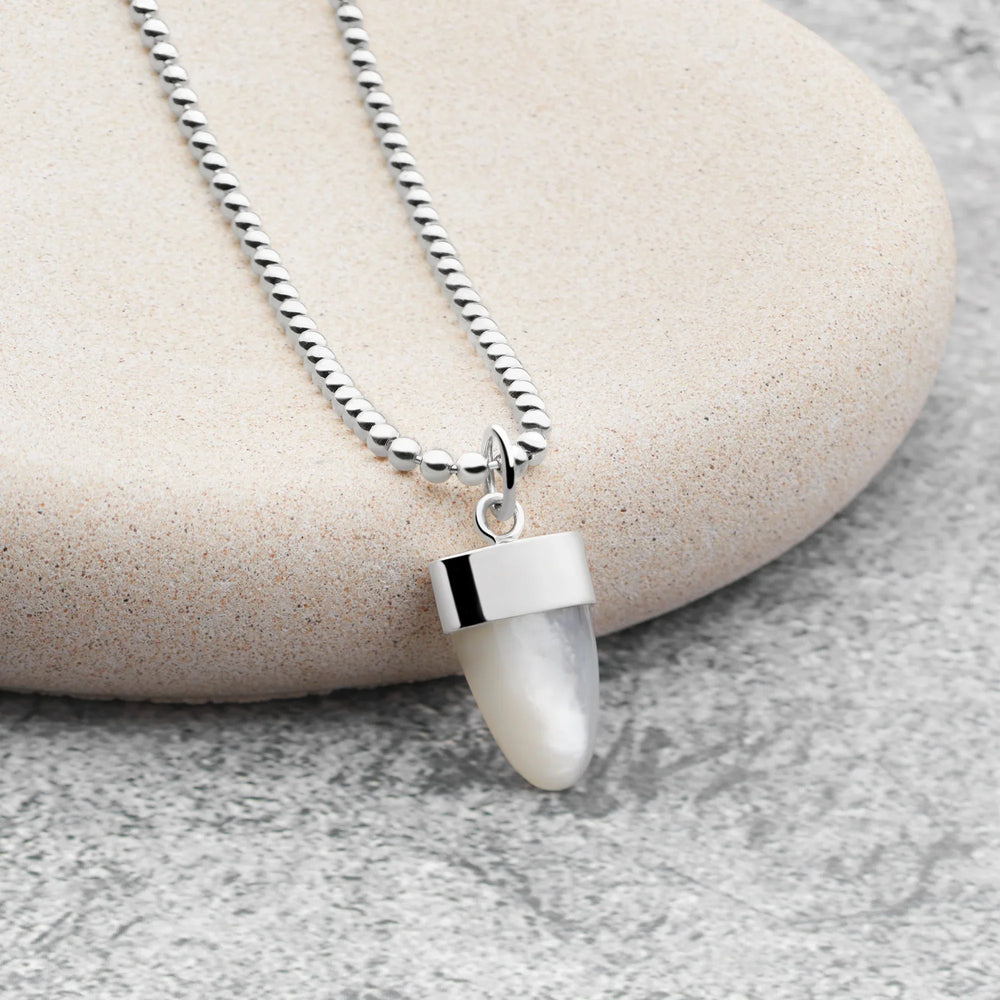 Necklace with a white pendant on a stone surface