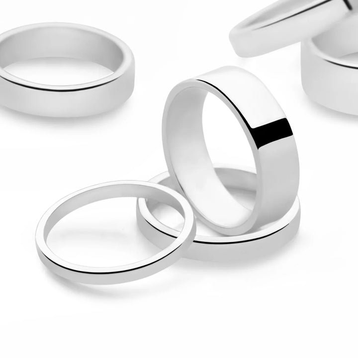 A flat silver band ring with a smooth finish and a width of 7mm white background. 