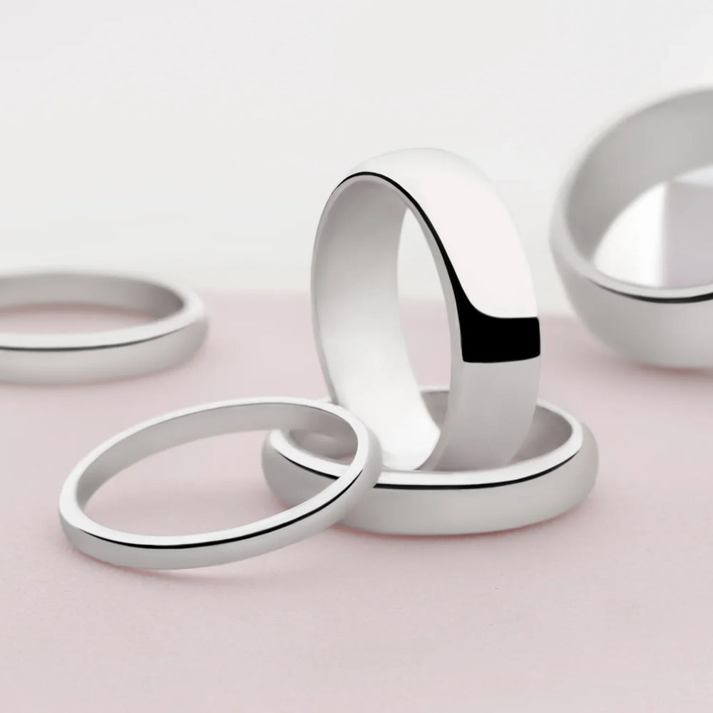 A D-shaped silver band ring with a smooth, polished finish on white background. 