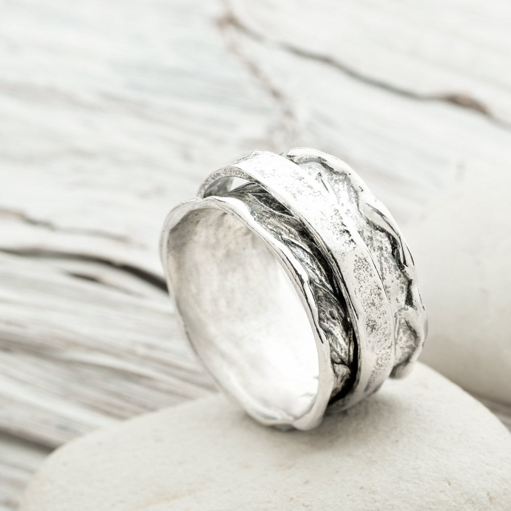A silver spinning ring with a hammered texture, displayed on a white surface.