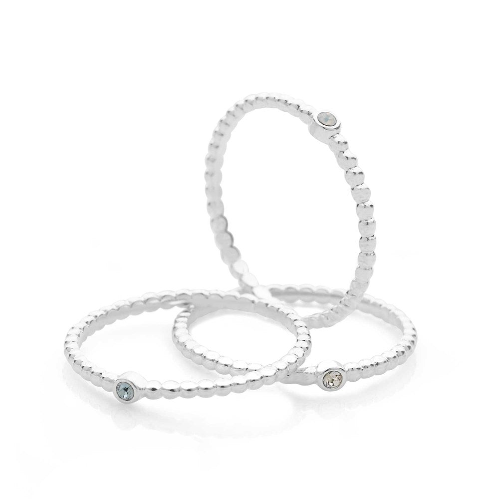 Three silver rings with beaded bands and a central faceted crystal design in a stack formation.