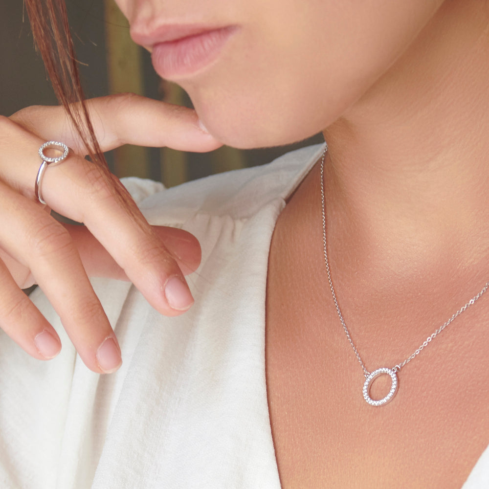 A sparkling halo ring with cubic zirconia stones set in a circle on a 925 sterling silver band with a high polish finish.