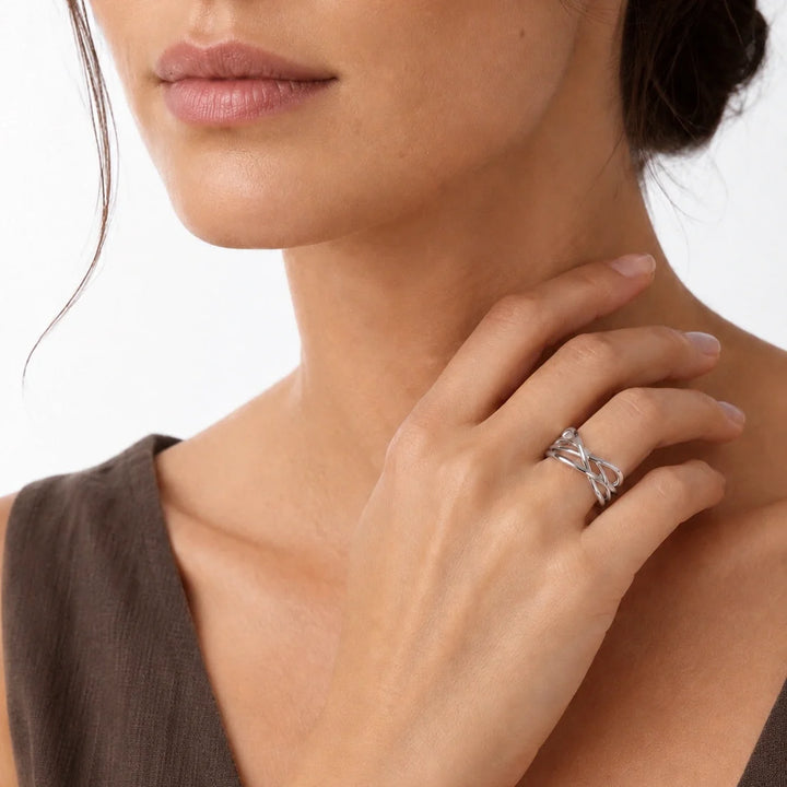 A model wearing a wide sterling silver crossover ring with smooth, intertwined multi-strand lattice bands.