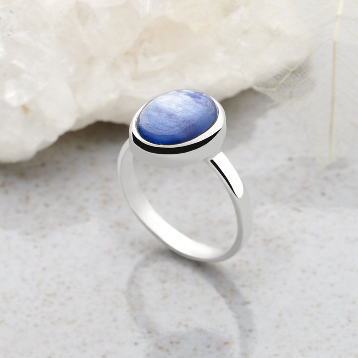 A ring with a central blue kyanite cabochon, set in a high polish finish 925 sterling silver band.