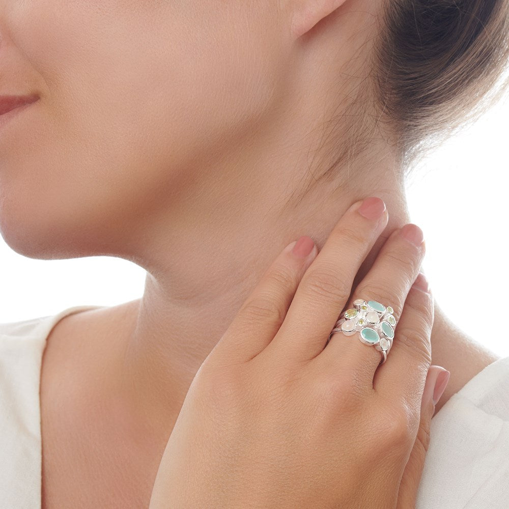 A silver ring with multiple translucent stones including aqua and peridot, set in a high polish finish female model. 