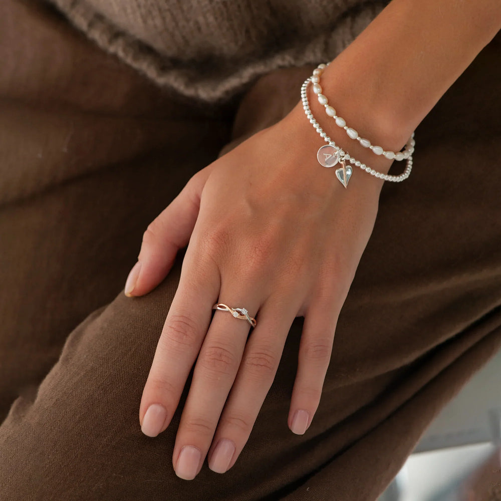 An eternity ring with two zirconia stones, entwined with silver and rose gold bands.