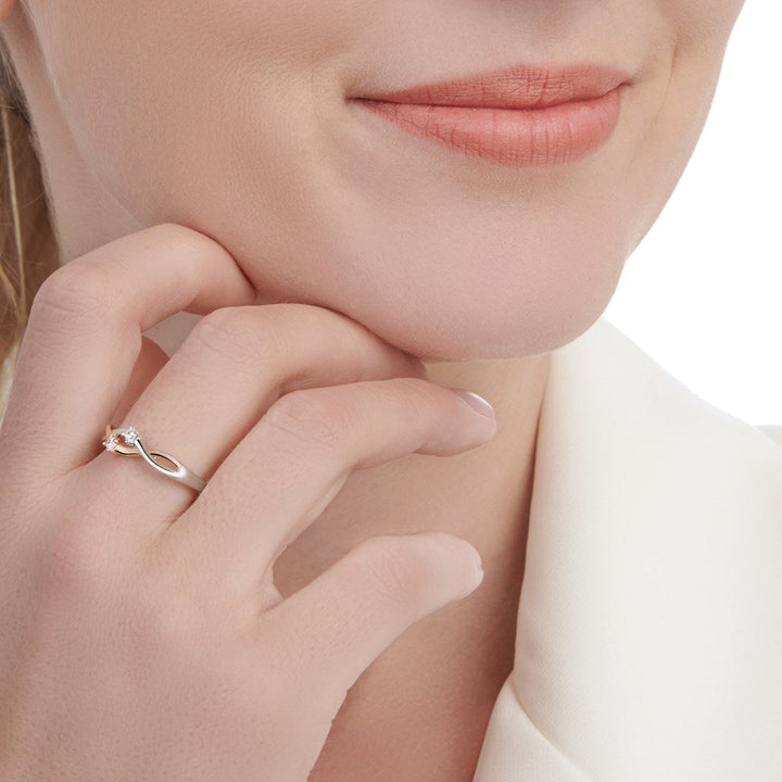An eternity ring with two zirconia stones, entwined with silver and rose gold bands. Female model. 