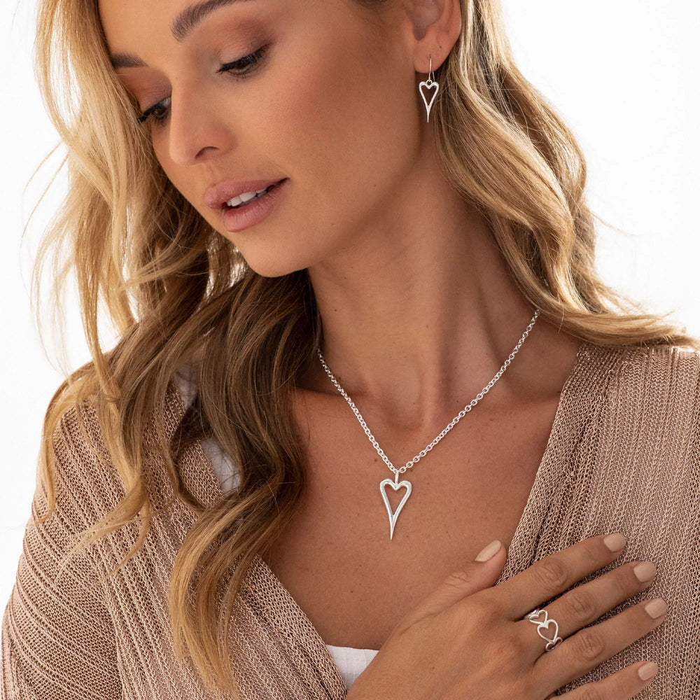 A silver ring with a design of multiple hearts fused together, displayed on a female model.