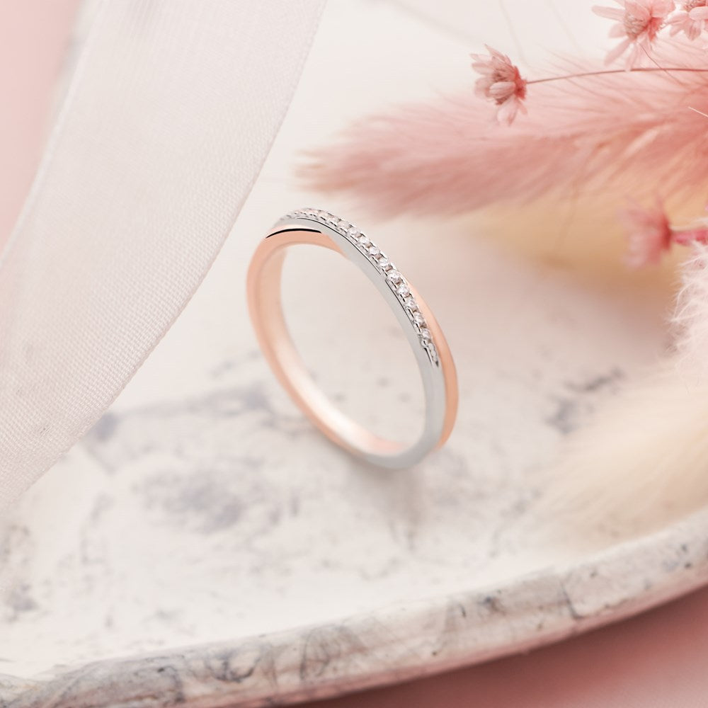 A chic silver and rose gold plated ring with sparkling cubic zirconia stones on the bridge on neutral background. 