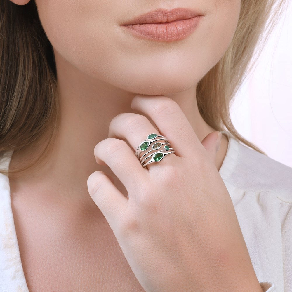 A silver ring with multiple bands and green onyx, hydro-quartz, and hydro-green amethyst stones set on a polishing cloth on model.