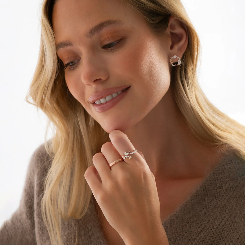 Woman wearing silver rings and earrings on a neutral background