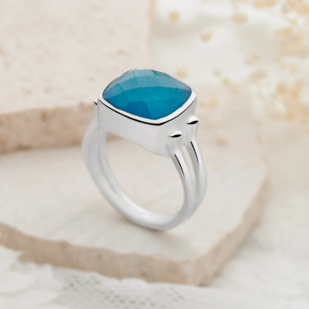Silver ring with a blue stone on a textured beige background