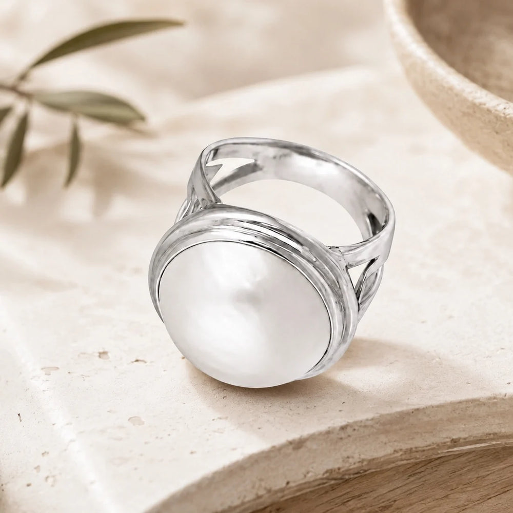 Sterling silver ring, large pearl stone, high polish finish, intricate design on band. 