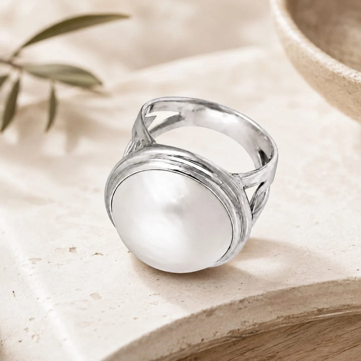 Sterling silver ring, large pearl stone, high polish finish, intricate design on band. 