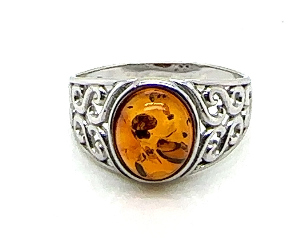 Silver ring with a amber stone on a white background celtic desing.